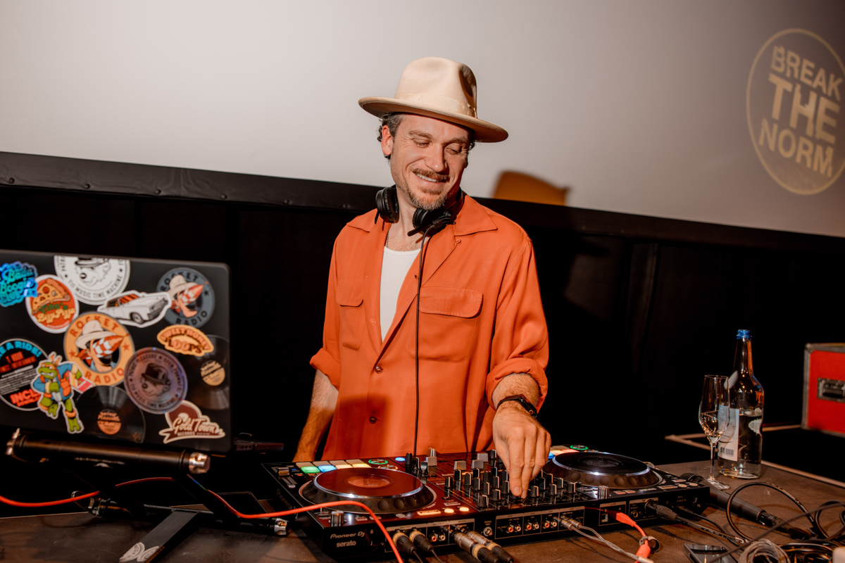 Patric Pleasure (DJ) mit orangem Hemd und Fedora-Hut heizt die Stimmung auf an der Break the Norm Party am HR FESTIVAL europe 2024.