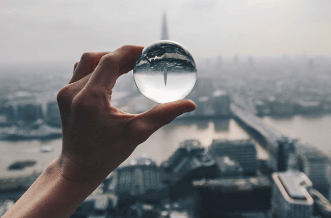 Eine Person hält eine Glaskugel hoch über die Stadt London als Symbolbild für Trends in der Zukunft