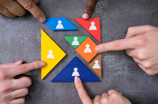 Hände schieben farbige Puzzleteile zusammen, symbolisch für Kompetenzen im Unternehmen, die sich ergänzen