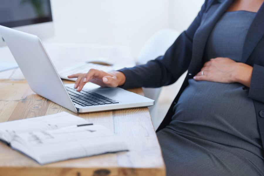 Une femme d'affaires enceinte travaille sur son ordinateur portable au bureau