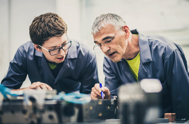 Ein älterer Handwerker erklärt einem jungen Handwerker was er tun muss