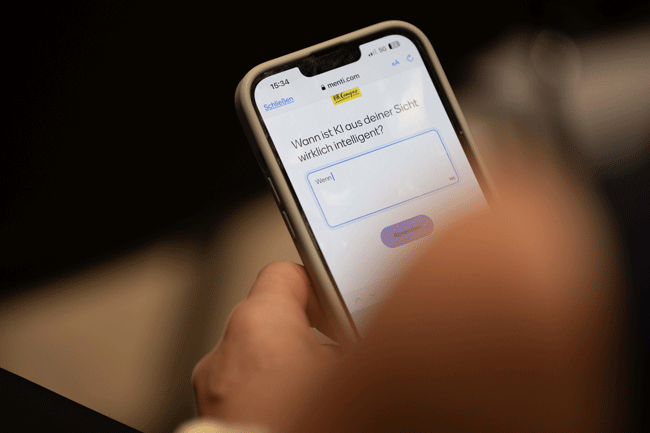 Blick auf ein Handy, das eine KI eine Frage stellt