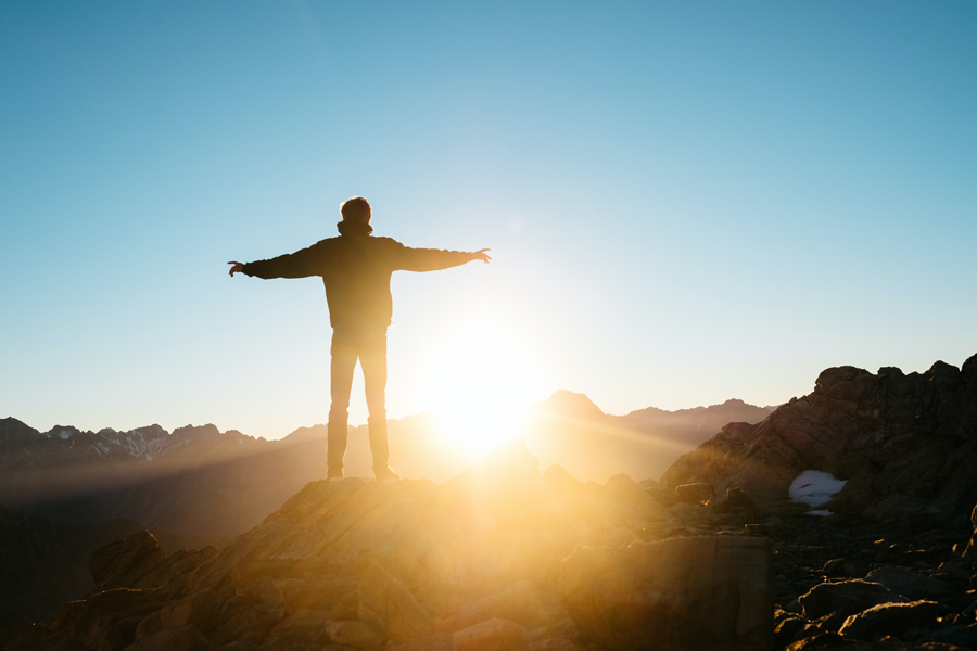 Un homme se tient debout seul face au soleil levant