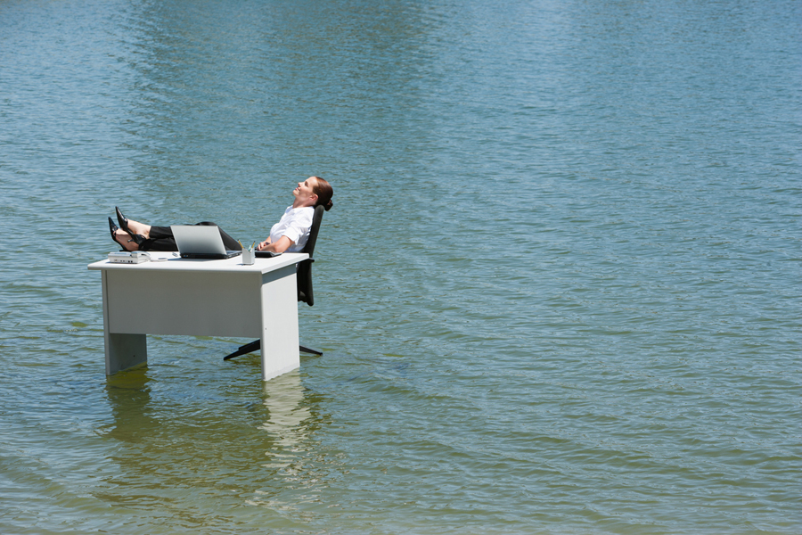 Une femme d'affaires est assise à son bureau installé dans l'eau