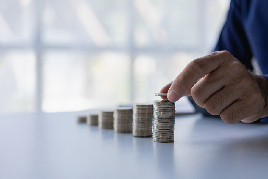 Un homme assis à un bureau complète des piles de pièces de monnaie