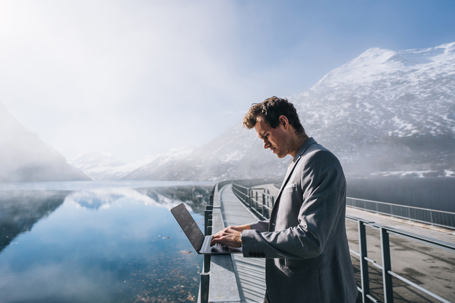 Un homme en costume avec son ordinateur portable dans les alpes suisses