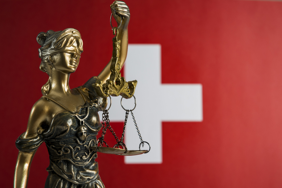 Une statue de la Justice devant un drapeau suisse