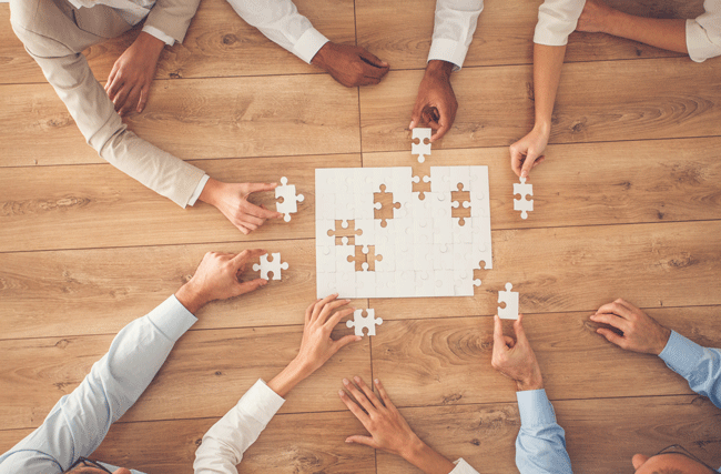 Gruppe von Mitarbeitenden setzt Puzzleteile zusammen