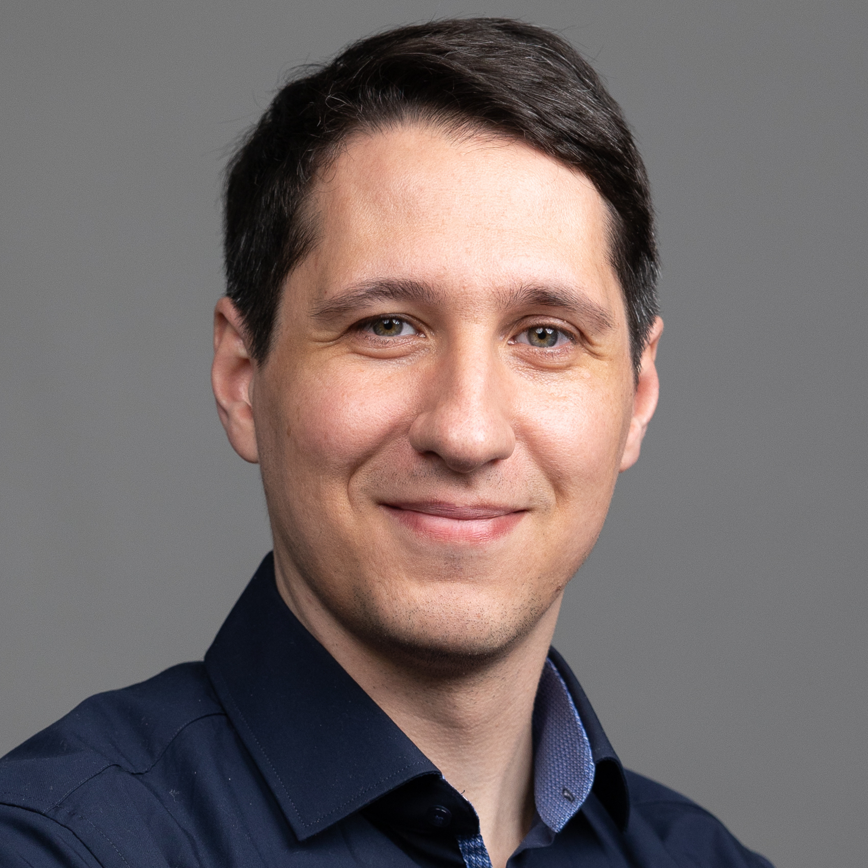 Das Bild zeigt Pablo Schmid, einen Mann mit kurzen dunklen Haaren mit Seitenscheitel. Er lächelt entspannt in die Kamera.