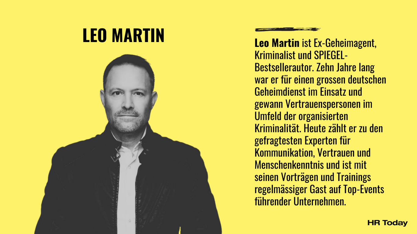 Porträt von Leo Martin, ein Mann mit kurzem dunklem Haar und leichtem Bart, frontal stehend vor hellem Hintergrund, bekleidet mit schwarzer Lederjacke über weissem Hemd und dunkler Hose. Beschreibung: Leo Martin ist Ex-Geheimagent, Kriminalist und SPIEGEL-Bestsellerautor. Zehn Jahre lang war er für einen grossen deutschen Geheimdienst im Einsatz und gewann Vertrauenspersonen im Umfeld der organisierten Kriminalität. Heute zählt er zu den gefragtesten Experten für Kommunikation, Vertrauen und Menschenkenntnis und ist mit seinen Vorträgen und Trainings regelmässiger Gast auf Top-Events führender Unternehmen.