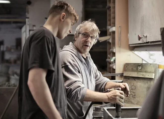 Un travailleur âgé forme un apprenti: les enjeux de l'employabilité des seniors en Suisse