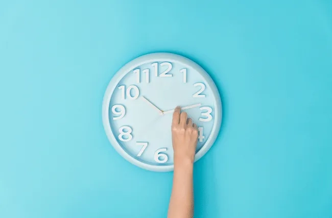 Eine Frau verstellt den Zeiger einer Uhr, symbolisch für die Zeiterfassung