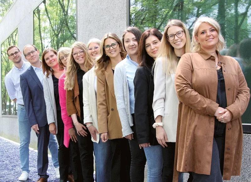 Das HR Team von adesso posieren der Reihe nach aufgestellt vor dem Hauptgebäude.