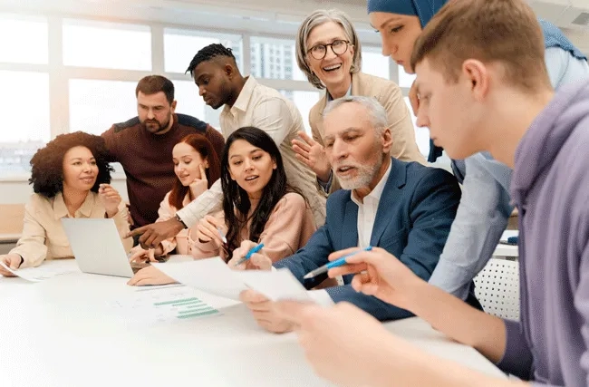 eine diverse Gruppe Menschen sitzen an einem Tisch im Büro