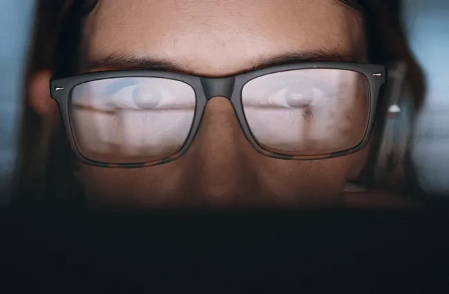 Frau mit Brille starrt auf Bildschirm