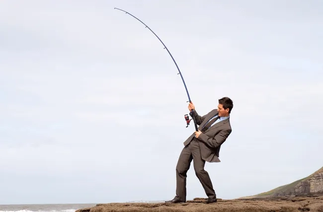 Mann im Business-Anzug angelt am Meer