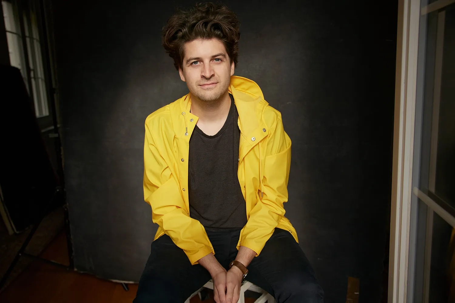 Das Bild zeigt Karpi, sitzend, mit gelber Jacke, leicht schalkhaft gerade in die Kamera blickend.