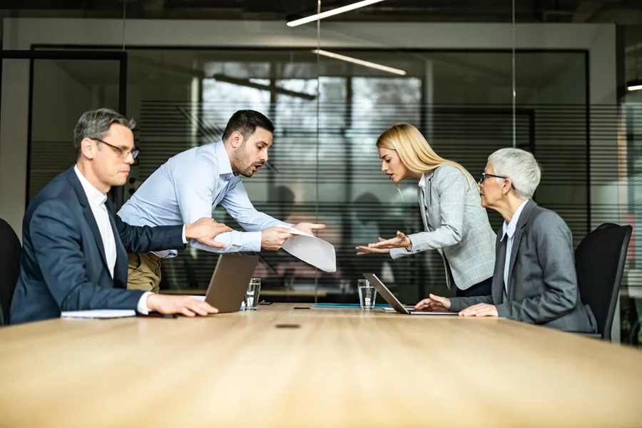 Des collègues frustrés se disputant au sujet d'un document lors d'une réunion