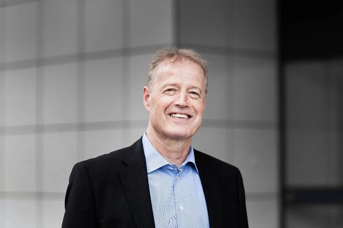 Gery Bruederlin, ein mittel-alter Mann, lächelnd mit Blazer und blauem Hemd.